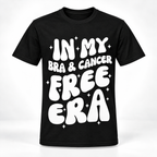 A black short-sleeve crewneck t-shirt with a bold white retro-style graphic reading 'IN MY BRA & CANCER FREE ERA' surrounded by small white star sparkles, shown on a clean white background.