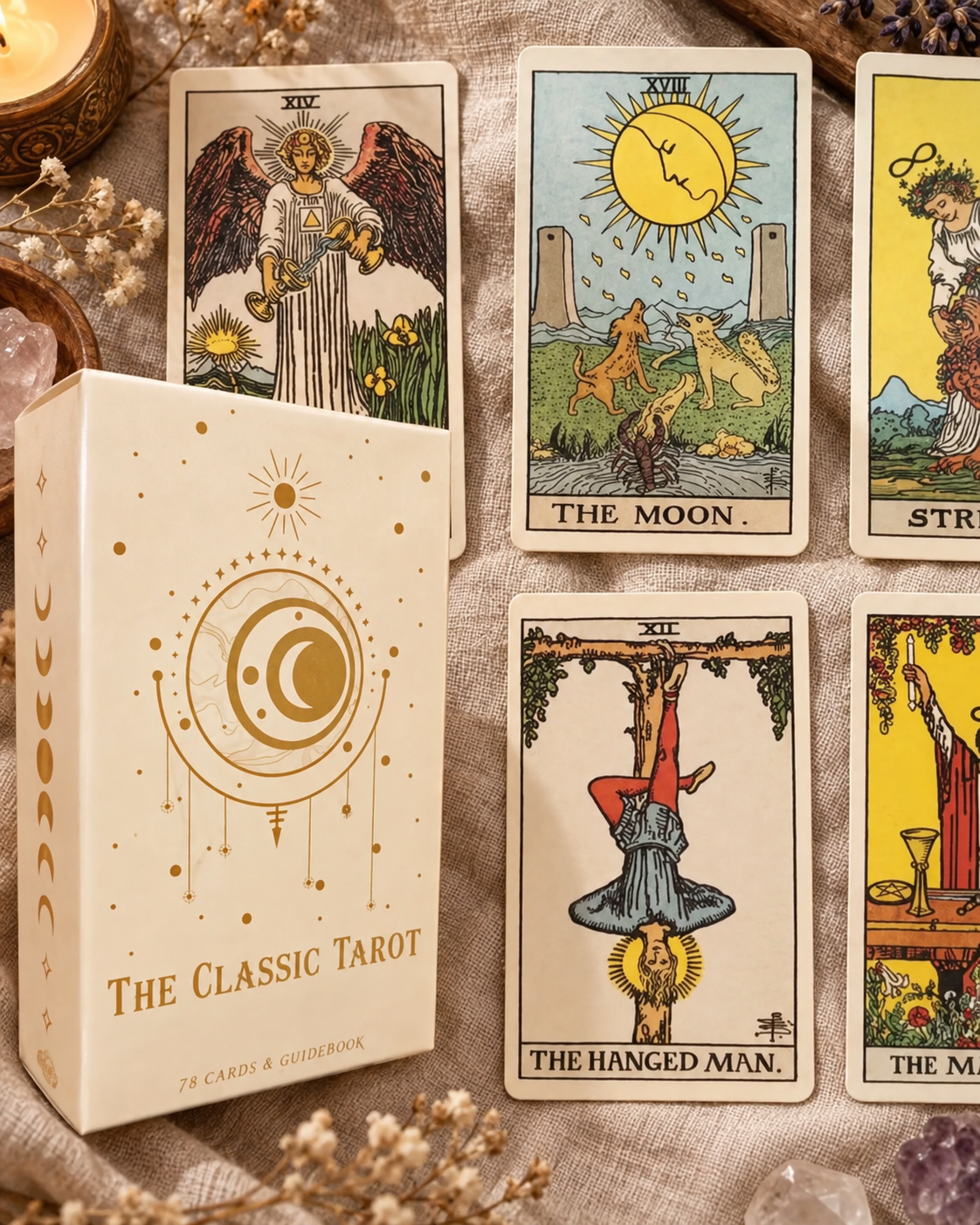 A boxed tarot card deck labeled 'The Classic Tarot' sits beside several illustrated tarot cards on a textured fabric surface, with candles and crystals as styled props.