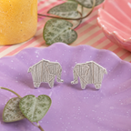 Elephant Stud Earring pair in sterling silver with textured origami-style elephant design on a speckled purple plate with string of hearts plant