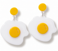 A pair of novelty egg-shaped drop earrings with bright yellow circular studs and centers on a clean white background.