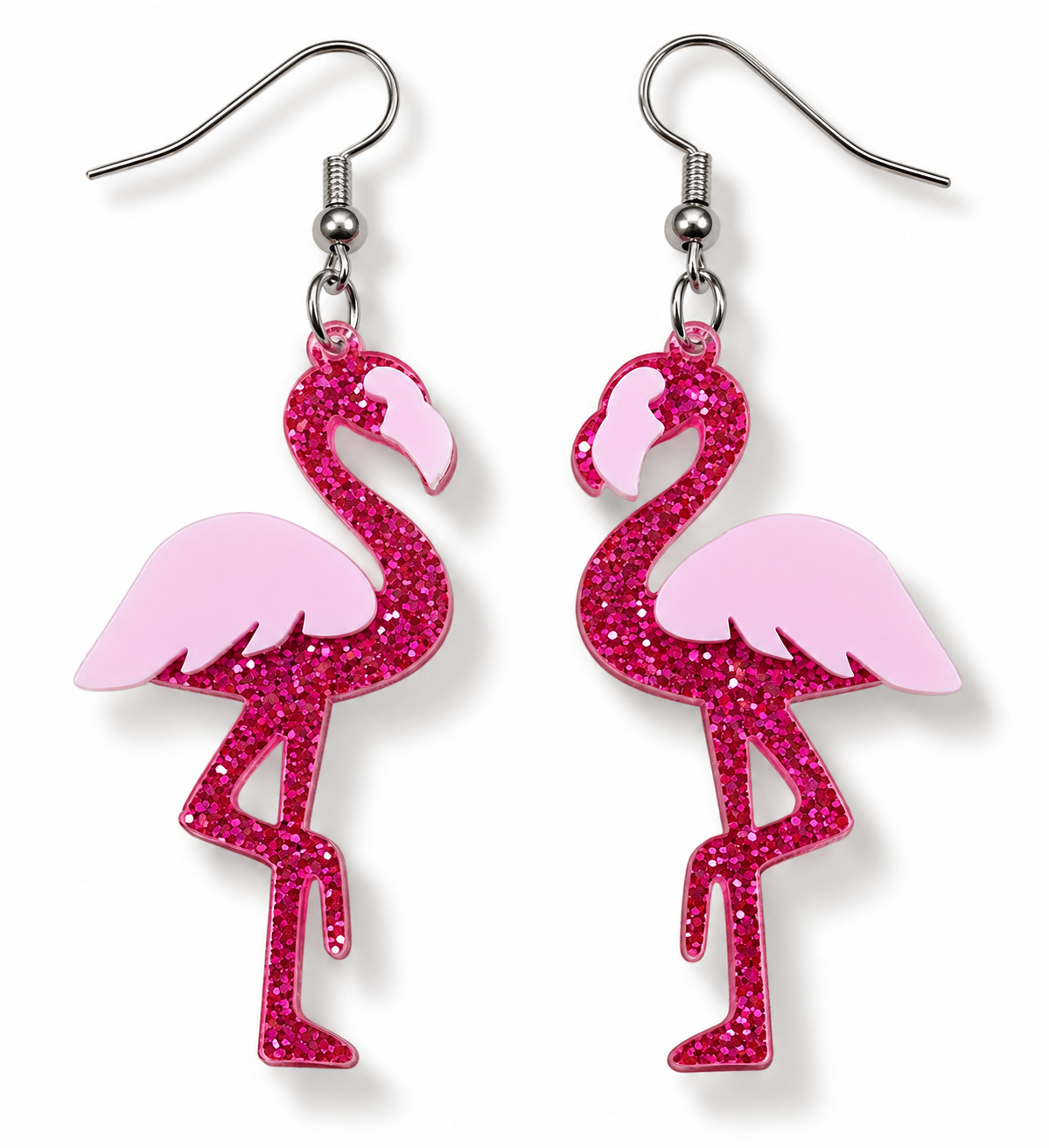 A pair of dangling earrings shaped like flamingos, with bright pink glitter bodies and pale pink wings, hanging from silver fishhook wires on a white background.