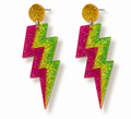 A pair of chunky lightning bolt drop earrings covered in glitter, featuring a bright pink and lime green zigzag body with a round gold glitter stud at the top.