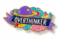 A colorful enamel pin featuring a purple space helmet, stars, swirls, and a ribbon banner with the word 'OVERTHINKER' in white letters on a dark blue background, outlined in gold against a white backdrop.