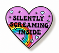 A heart-shaped enamel pin with a light purple background, black border, and the text 'SILENTLY SCREAMING INSIDE' in black. A rainbow arc and small hearts, stars, and flowers decorate the design.