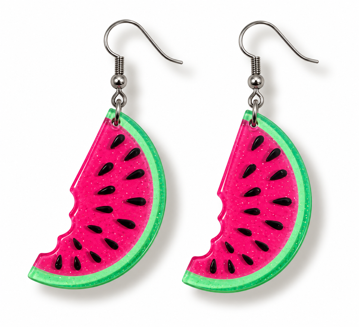 A pair of watermelon slice drop earrings with bright pink glitter-filled centers, green rinds, and black seeds, suspended from silver fishhook wires on a white background.