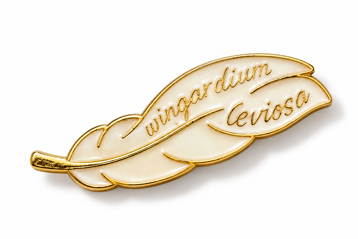 A feather-shaped enamel pin with gold metal outlines and cream-colored enamel fill, featuring the cursive text 'wingardium leviosa' on a clean white background.